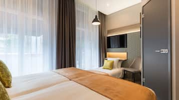 A hotel room with a bed, a desk, a chair, a TV, and a wardrobe.
