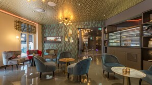 A modern lounge area with seating, a bar, and a patterned ceiling.