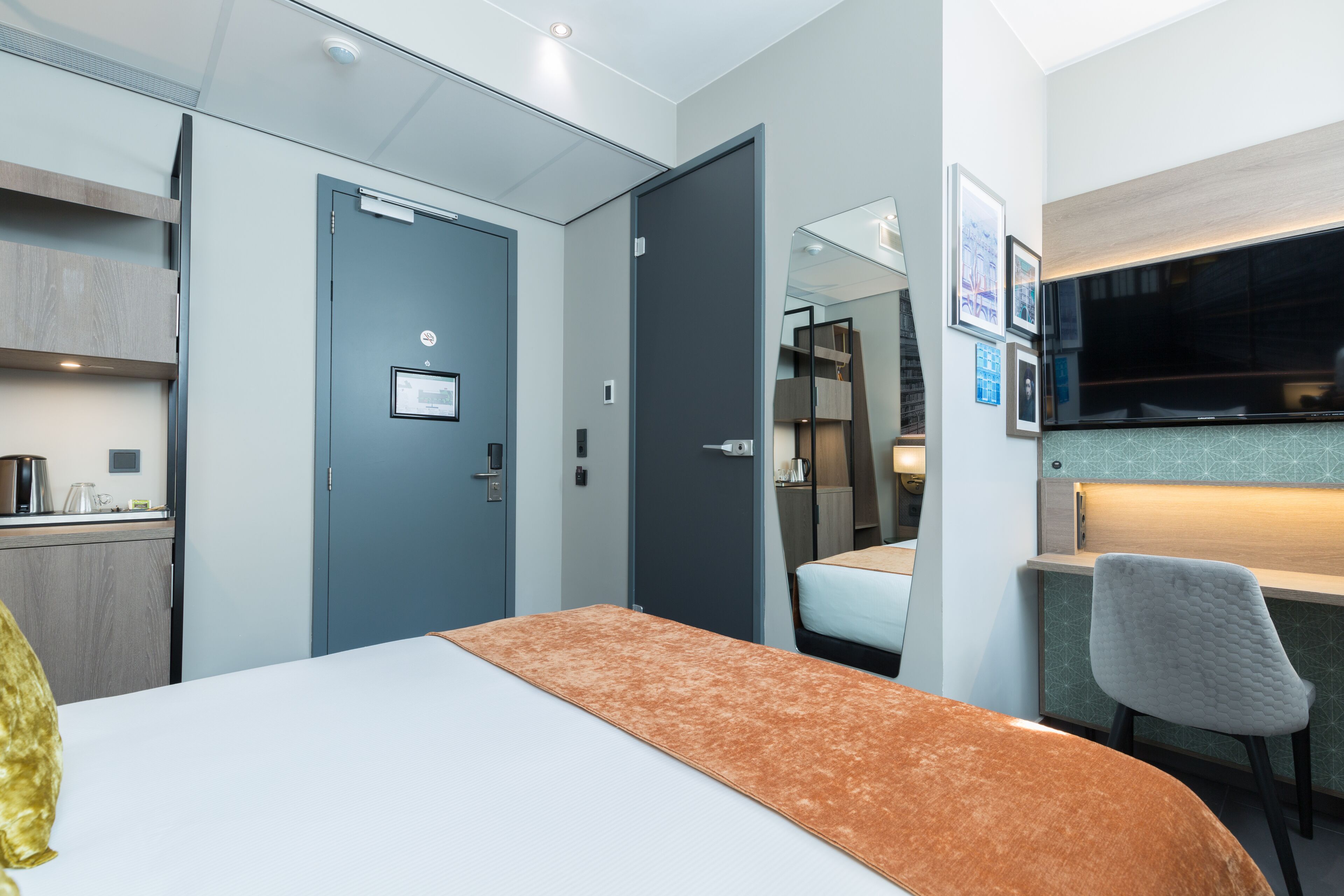 A hotel room with a bed, a desk, a chair, a wardrobe, and a bathroom.