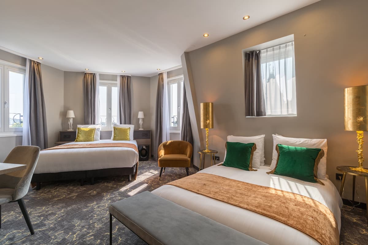 Hotellihuone, jossa on kaksi sänkyä, työpöytä, tuoli ja suuri ikkuna.