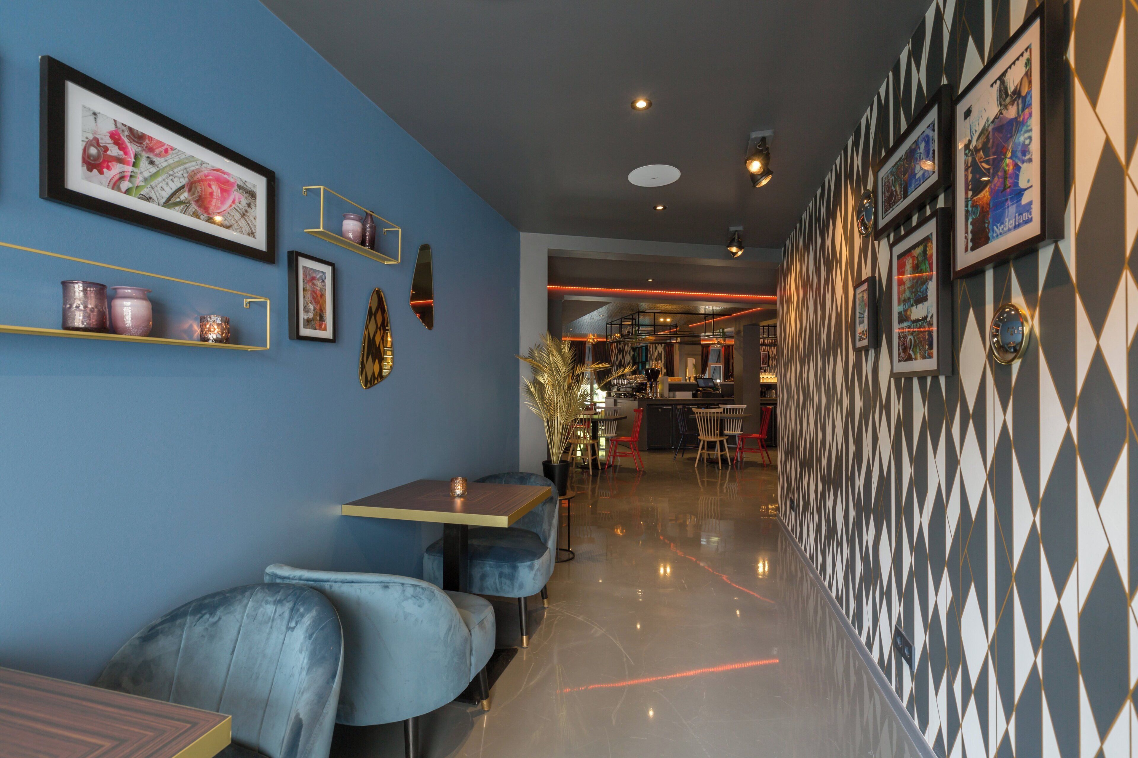 Un interior moderno con paredes azules, una zona de bar y asientos frente a una pared con diseño.