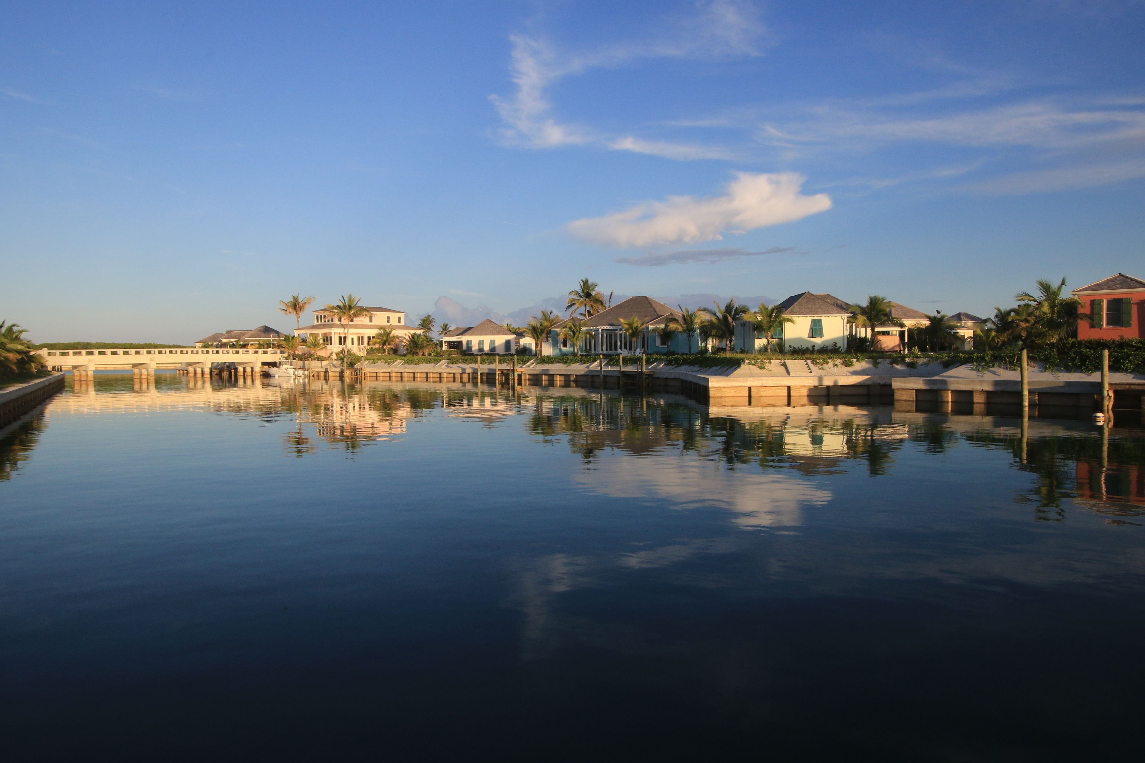 A waterfront property with a bridge, reflecting buildings, and palm trees.