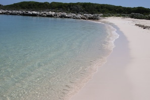 A beach with clear turquoise water, white sand, and rocky outcrops. - The Sandpiper Inn & Cottages (Crossing Rocks)
