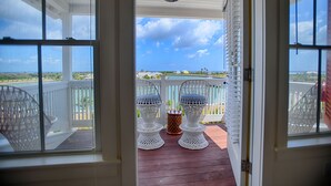 A view from a porch with a railing, two wicker chairs, and a small table. - The Sandpiper Inn & Cottages (Crossing Rocks)