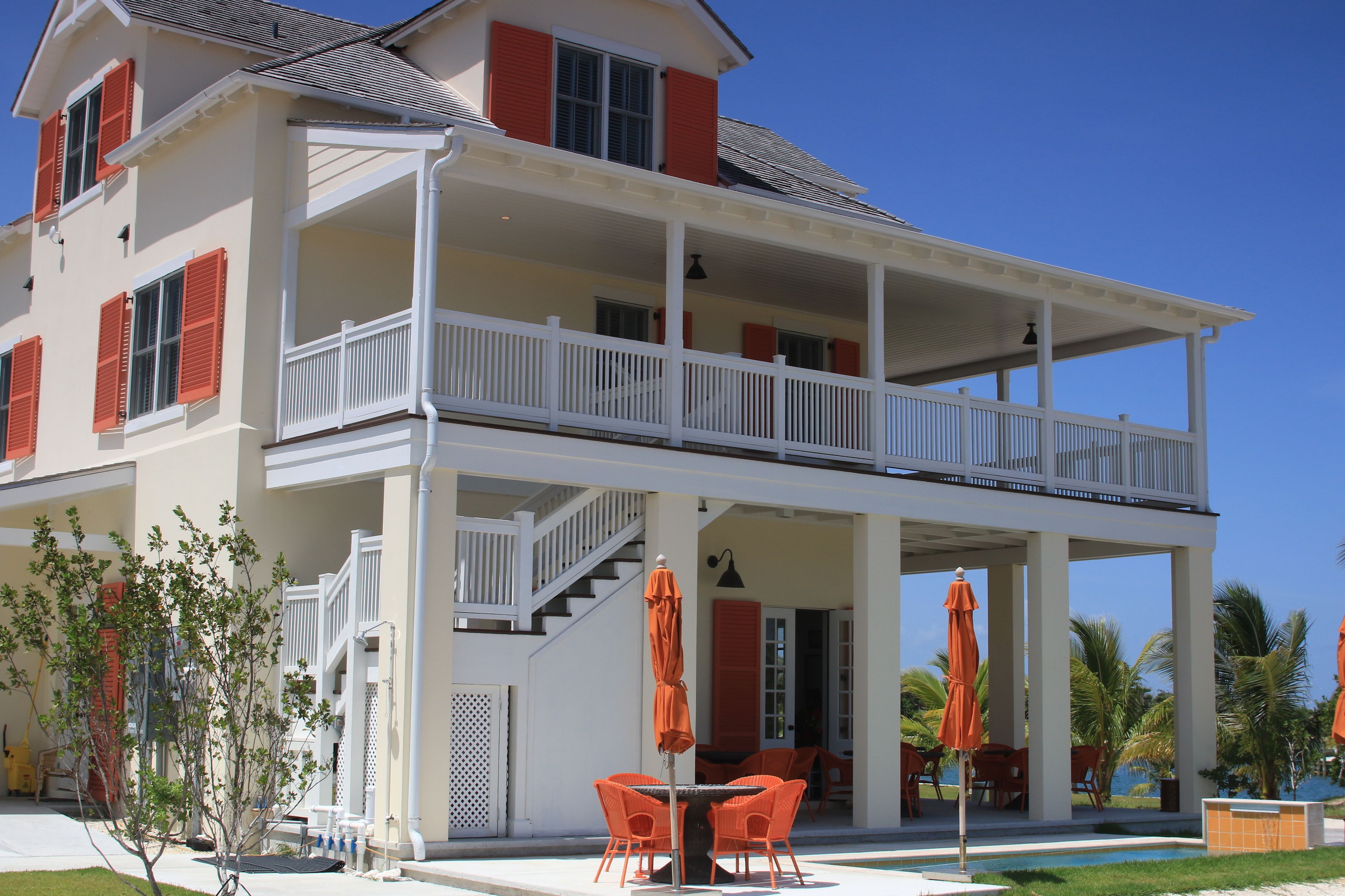 A two-story house with a balcony, outdoor seating, and a pool.