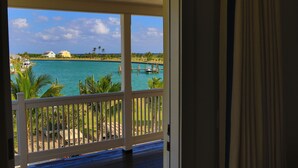 A view from a room with a white railing, overlooking a turquoise sea with boats, palm trees, and buildings in the distance. - The Sandpiper Inn & Cottages (Crossing Rocks)