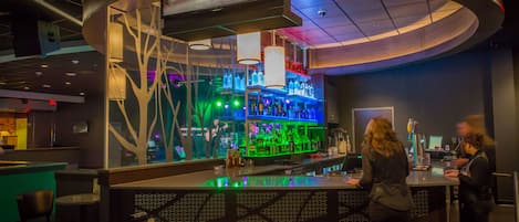 A bar area with a curved counter, seating, and a television screen.