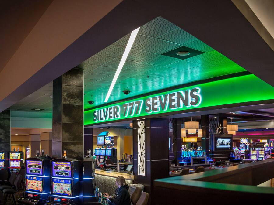Een casino met gokkasten en een neonbord waarop staat
