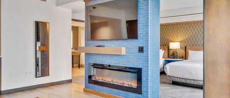 Una habitación de hotel moderna con chimenea, un espejo grande y una cama con cabecero.