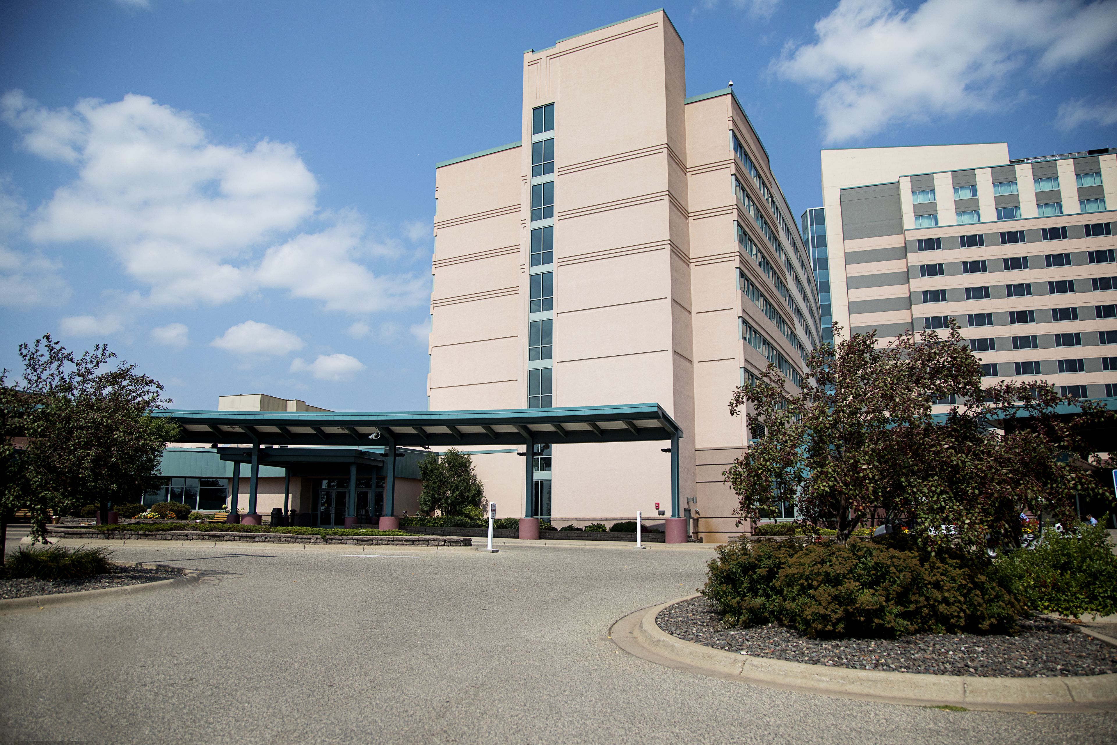 A multi-story hotel with a covered entrance and a parking lot.