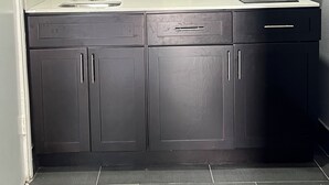 A modern kitchen with dark cabinets, a stainless steel sink, and a microwave above the countertop. - Airway Inn - IAH Airport (Houston)