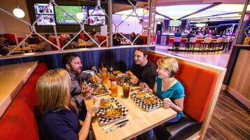 A group of people dining at a restaurant with multiple screens displaying sports events in the background.