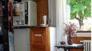 A compact kitchen with wooden cabinets, a small refrigerator, and a window with a view of greenery. - Hosteria Sur (San Carlos de Bariloche)