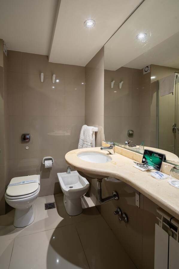 A modern bathroom with a toilet, bidet, sink, and mirror.