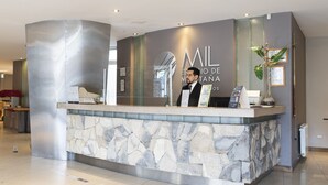 Un mostrador de recepción con fachada de piedra y separador de vidrio, que muestra el logo 'ML' y el texto 'ESTUDIO DE RESTAURANTE LOS'.
