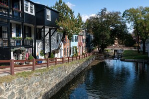 Un edificio a la orilla de un canal, con pared de piedra, valla de madera y un pequeño muelle.