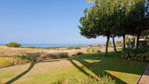 A well-maintained lawn with a clear view of the ocean, a few trees, and a concrete pathway. - Kumulani F 2 (Kamuela)
