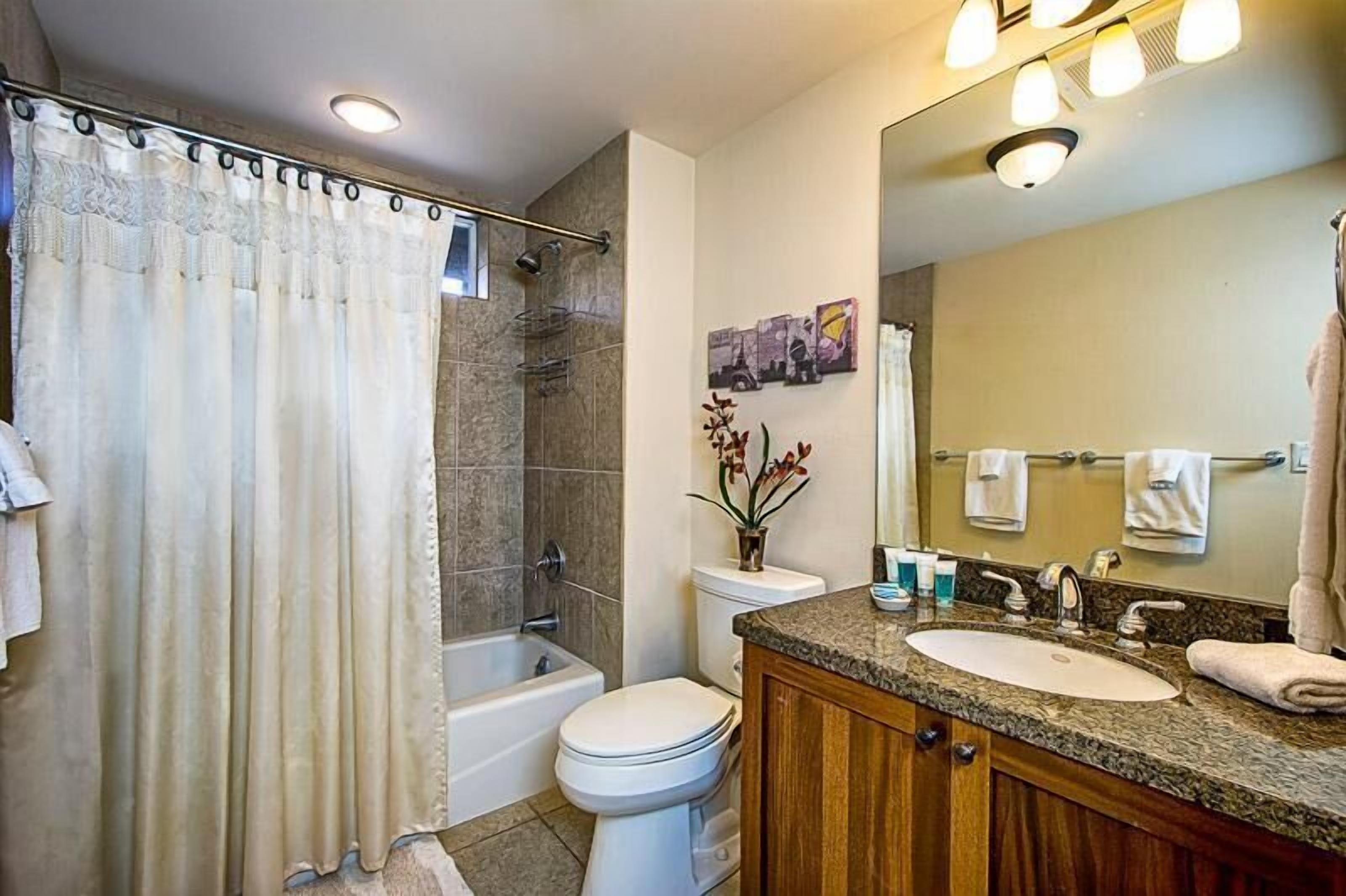 A bathroom with a bathtub, toilet, sink, and a large mirror.