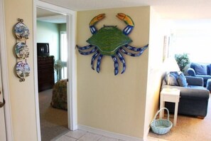 A living room with a decorative crab wall art, a white side table, and a blue sofa.