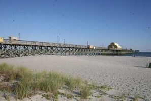 Ein Strand mit einem Steg, der sich ins Wasser erstreckt, mit einer großen Kuppelstruktur.