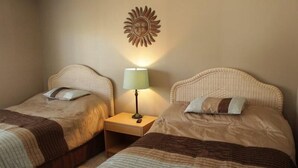 A hotel room with two single beds, a nightstand with a lamp, and a wall-mounted sun decoration. - Lake Arrowhead Fiesta (Myrtle Beach)