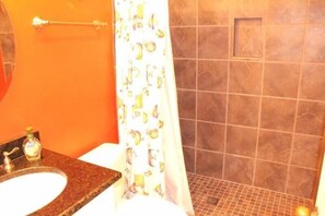 A bathroom with a granite countertop sink, a toilet, and a shower area with a tiled wall and a shower curtain. - Lake Arrowhead Base (Myrtle Beach)