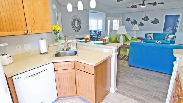 A modern kitchen with wooden cabinets, a dishwasher, and a central island with a sink. - Lake Arrowhead Recess (Myrtle Beach)