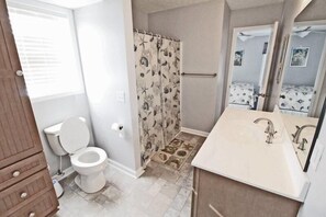 A bathroom with a toilet, shower curtain, sink, and mirror. - Lake Arrowhead Recess (Myrtle Beach)