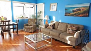 A living room with a sofa, armchair, coffee table, and dining table. - Lake Arrowhead Casa (Myrtle Beach)