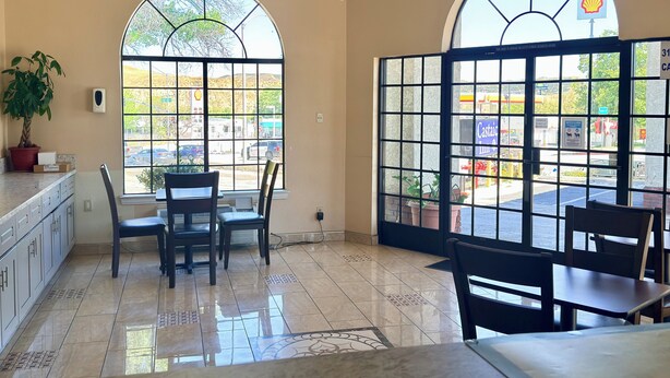 A room with two large windows, a chandelier, and a potted plant. - Castaic Inn Near Six Flags Magic Mountain (Castaic)