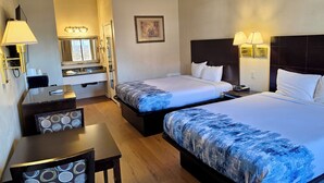 A hotel room with two beds, a desk, a chair, a vanity with a mirror, and wall-mounted lamps. - Castaic Inn Near Six Flags Magic Mountain (Castaic)