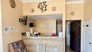 A hotel reception area with a tiled counter, a clock, and a sign for Casta Inn. - Castaic Inn Near Six Flags Magic Mountain (Castaic)