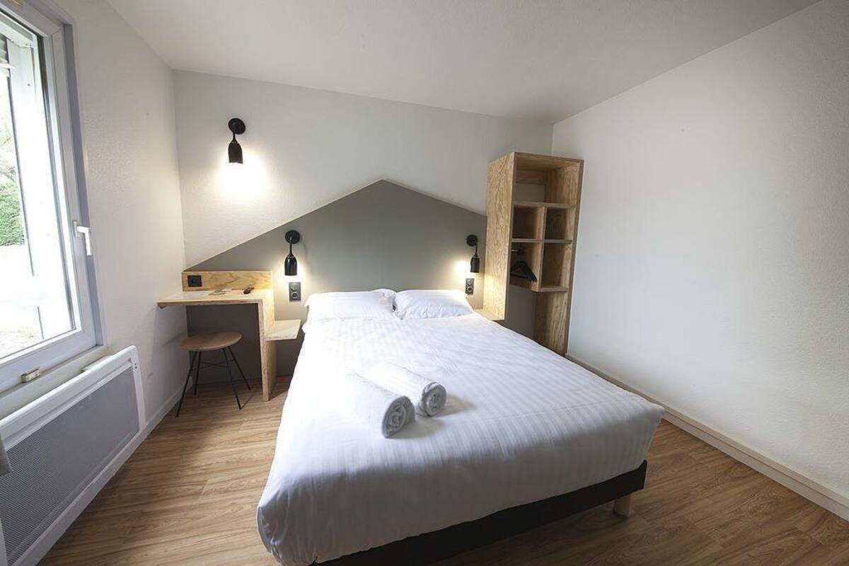 A bedroom with a bed, a desk, and a chair.