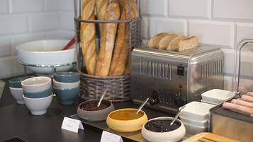 Un bufé de desayuno con pan, mermeladas y un tostador.