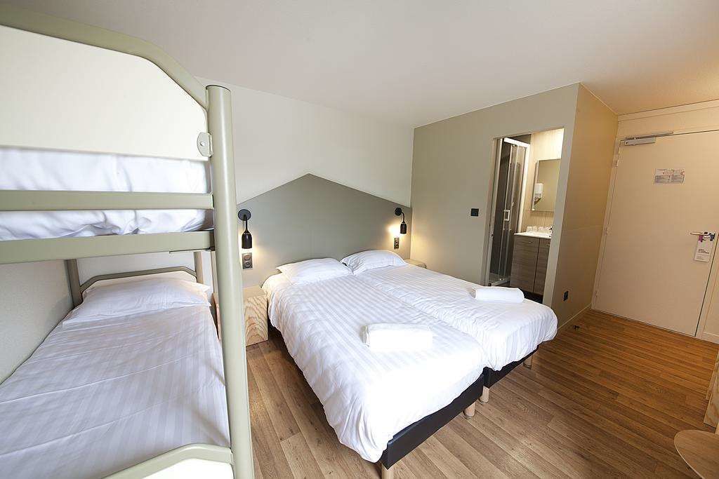 A room with bunk beds, a wooden floor, a mirror, and a door.