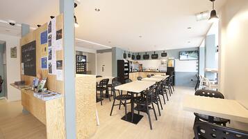 A modern restaurant with a wooden counter, black chairs, and a long dining table.