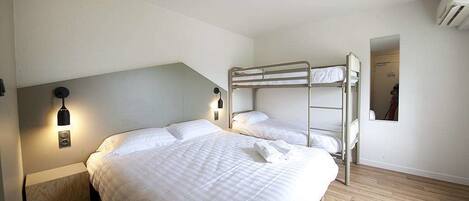 A bedroom with a bunk bed, a bedside table, a lamp, and a wall-mounted air conditioner.