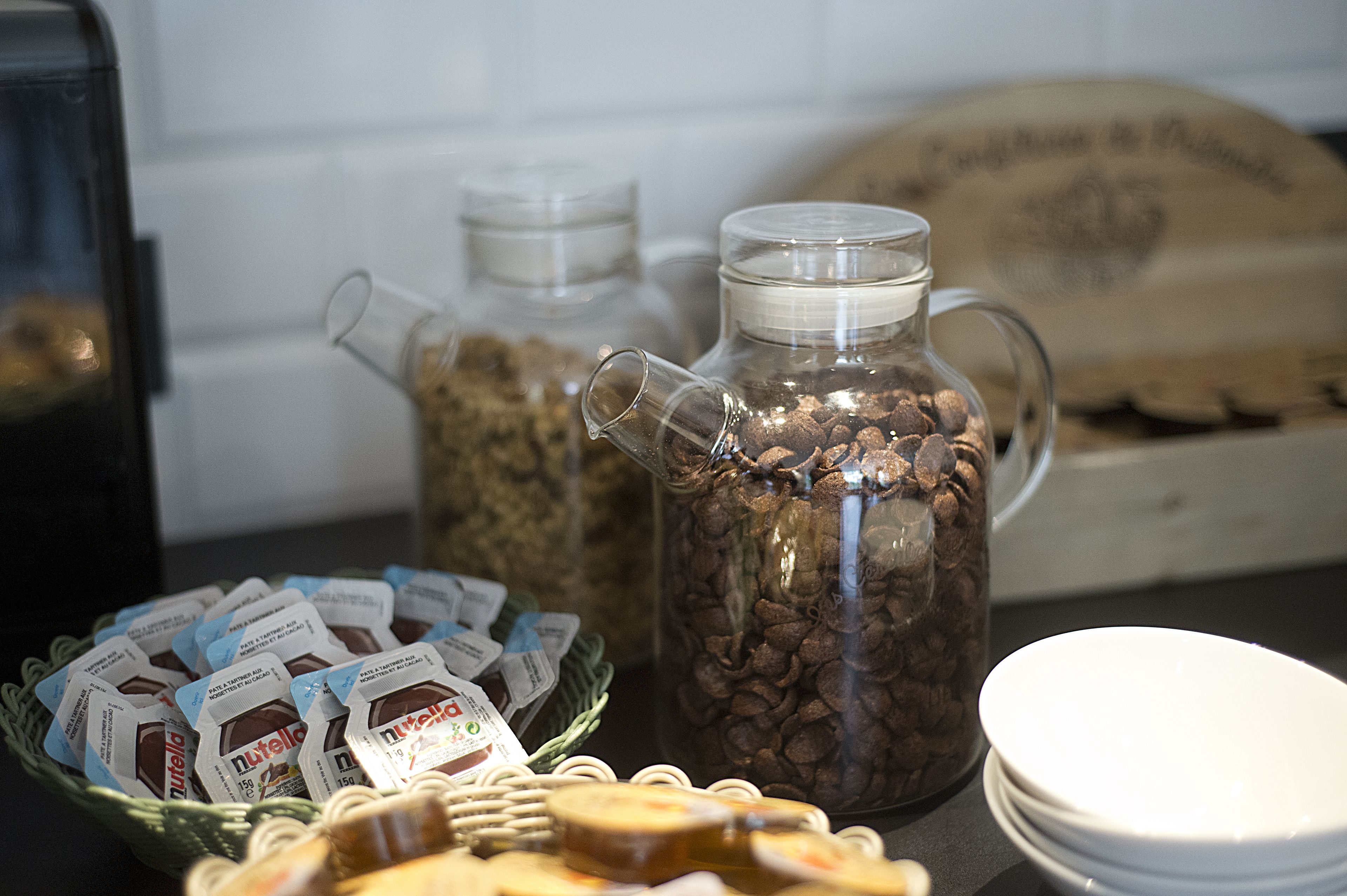 Una estación de café con un molinillo, un tarro de vidrio lleno de granos de café y un cesto de cápsulas de café.