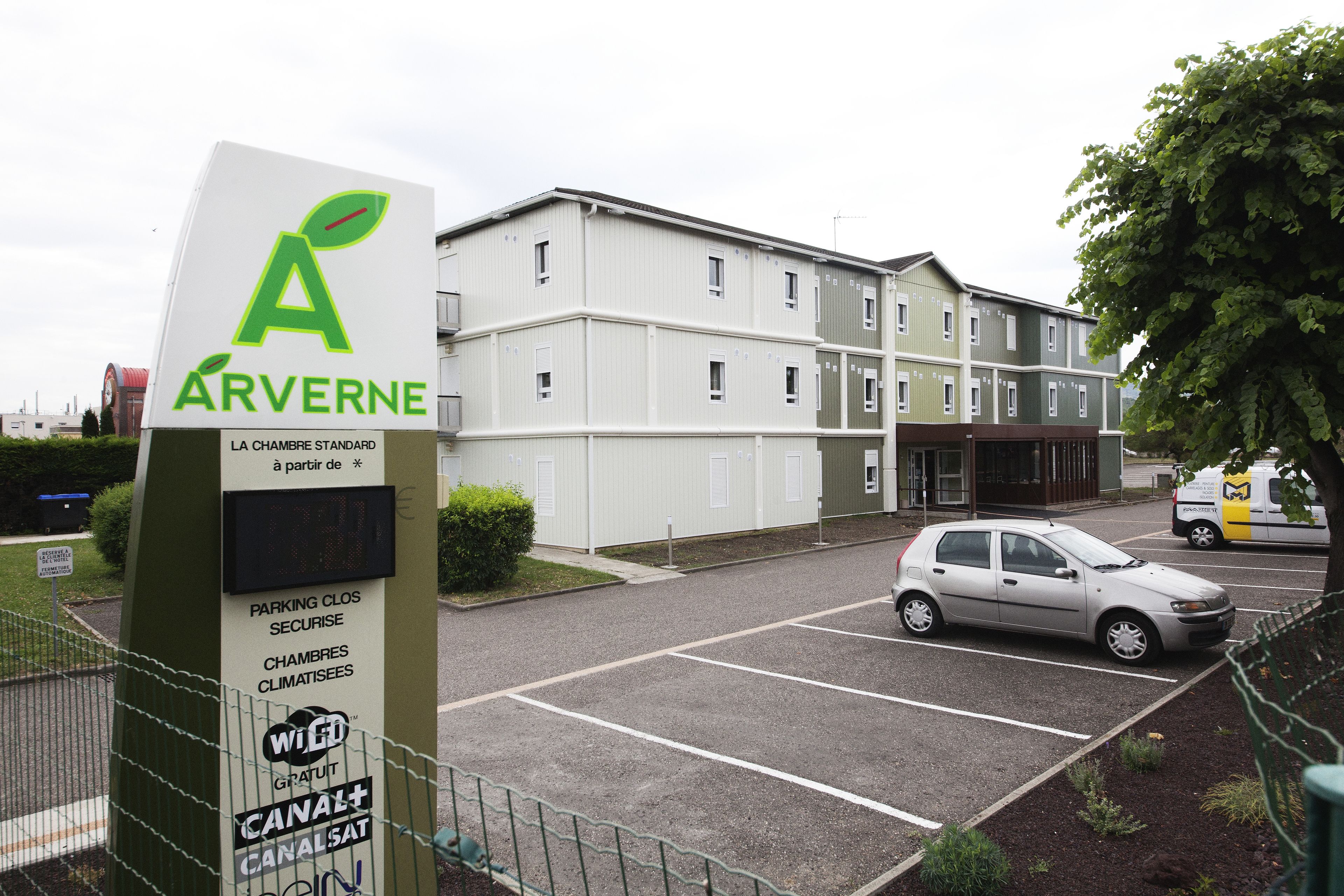 A hotel entrance with a sign for 'Arverne' and a parking area with a car.