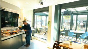 A modern kitchen with a large TV, a counter with food items, and a view of the outdoor seating area.