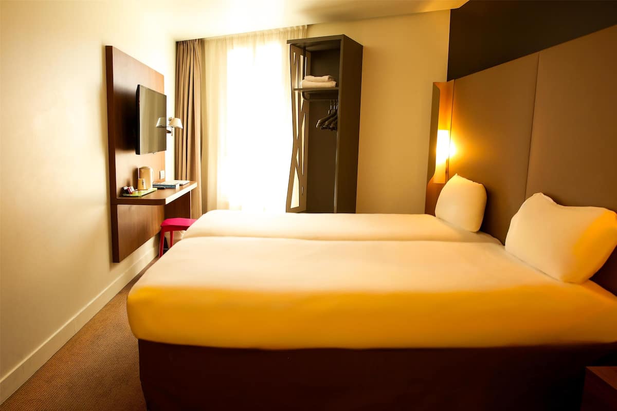 Une chambre d’hôtel avec un grand lit, un bureau doté d’un téléviseur à écran plat, une armoire et une lampe de chevet.