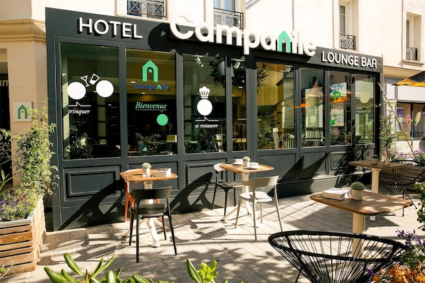 A hotel with a lounge bar, outdoor seating, and a clear view of the interior through large windows. - Campanile Paris - Clichy Centre (Clichy)