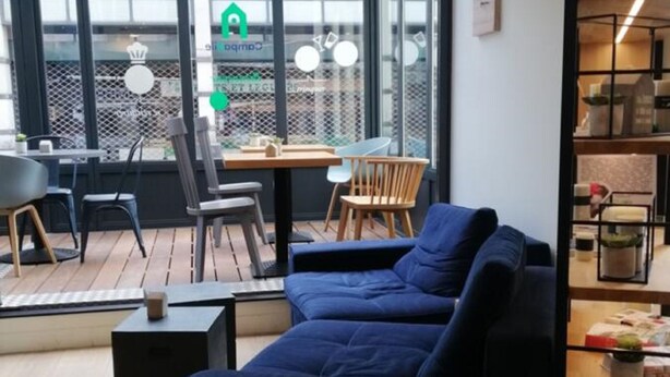Una sala de estar moderna con un sofá seccional, un comedor con mesa y sillas, y un ventanal con vista a la ciudad.