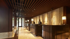 A hotel reception area with a modern design, featuring a long reception desk, a clock, and a well-lit interior.