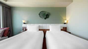 A hotel room with two beds, a green wall, and a decorative plant.