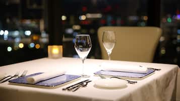 A dining table set with white tablecloth, blue patterned placemats, and two wine glasses.