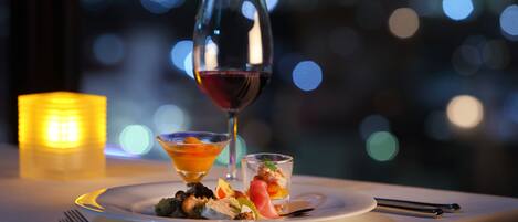 Una mesa dispuesta con una copa de vino, dos vasos de postre pequeños y un plato con comida.