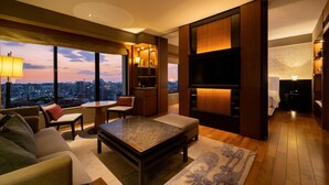 A modern living room with a city view, a large flat-screen TV, and a cozy seating area.