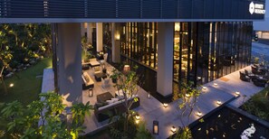 A modern hotel lobby with a pool, outdoor seating, and a view of the interior through large windows. - Hyatt Regency Naha, Okinawa (Naha)