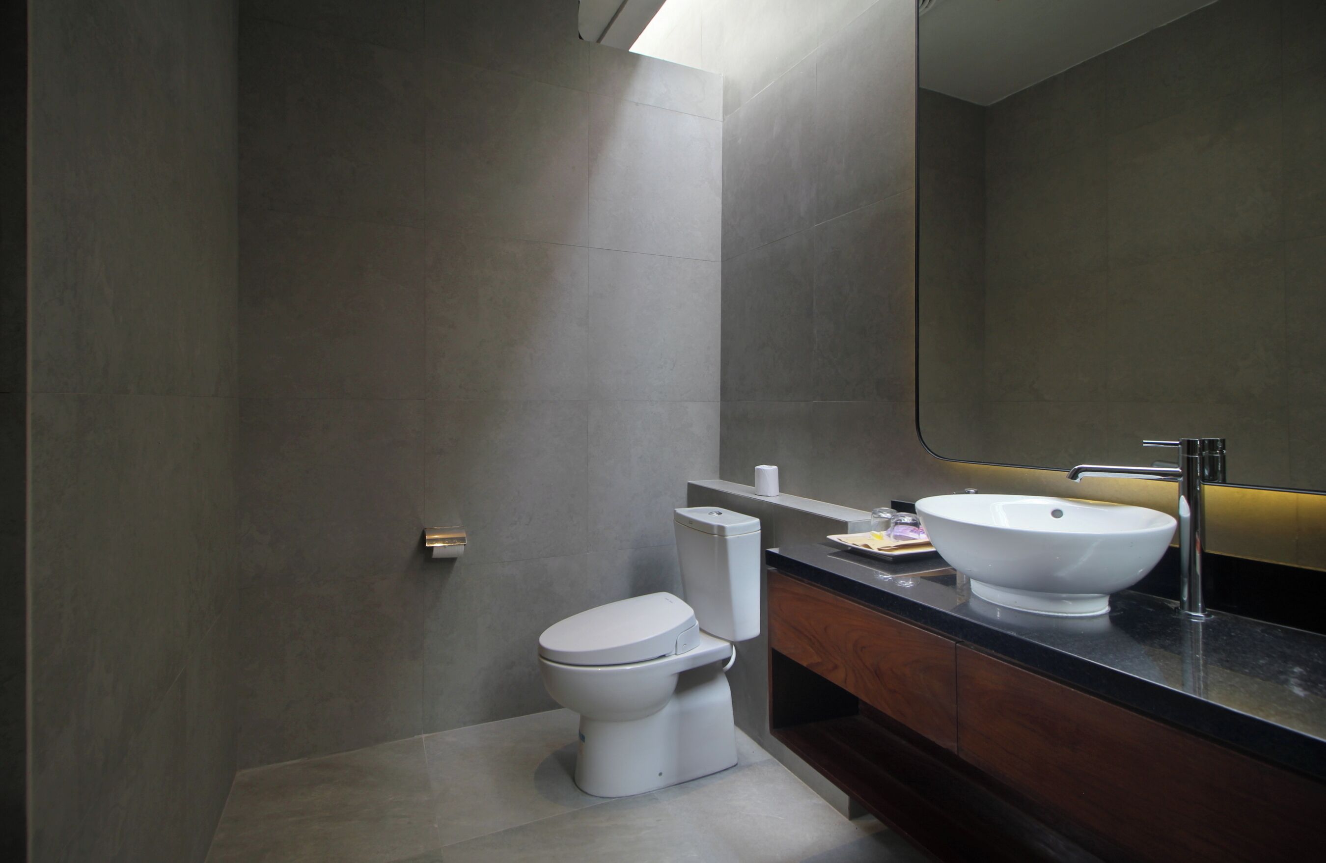 Ein modernes Badezimmer mit Toilette, Waschbecken und Spiegel.